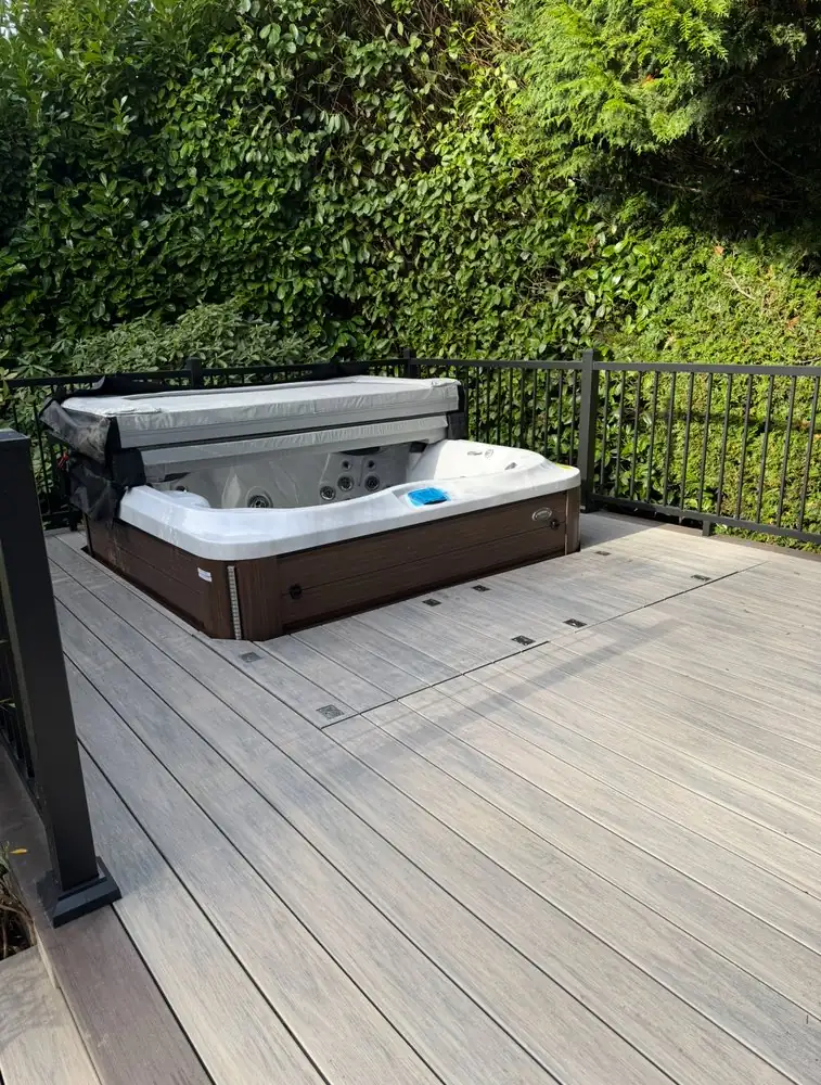 Deck surface and black railing around a hot tub
