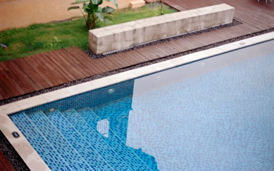 Wood decking beside a swimming pool with tiled entry steps