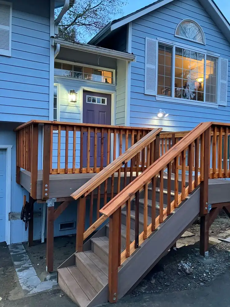 Wood deck stairs and railing beside a blue house